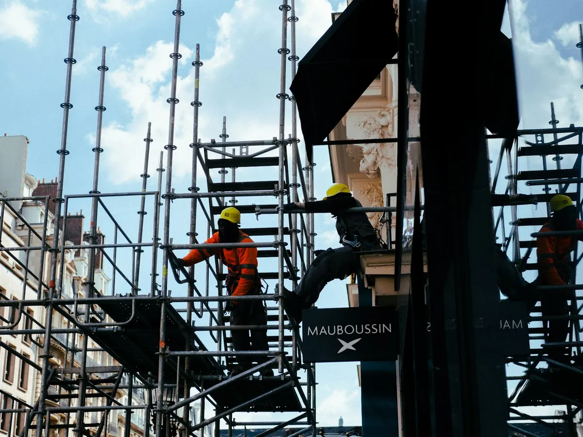 Equipa de obra com capacetes a trabalhar nos andaimes de um edifício